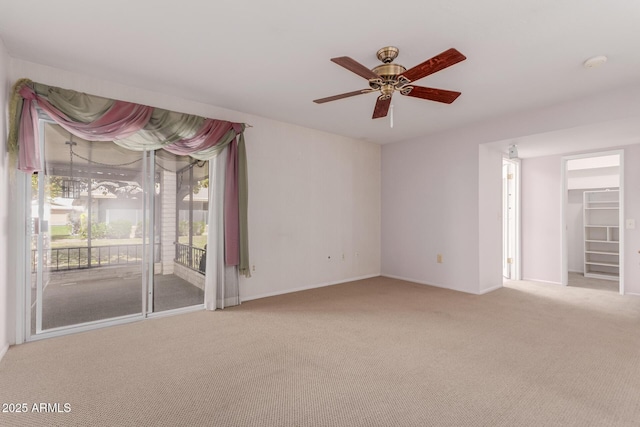 carpeted spare room featuring a ceiling fan and baseboards