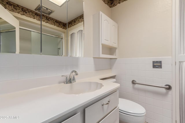 bathroom with tile walls, visible vents, toilet, an enclosed shower, and vanity