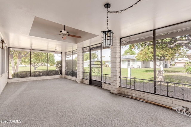 unfurnished sunroom with ceiling fan and a raised ceiling