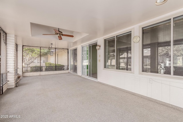 unfurnished sunroom with a tray ceiling and a ceiling fan