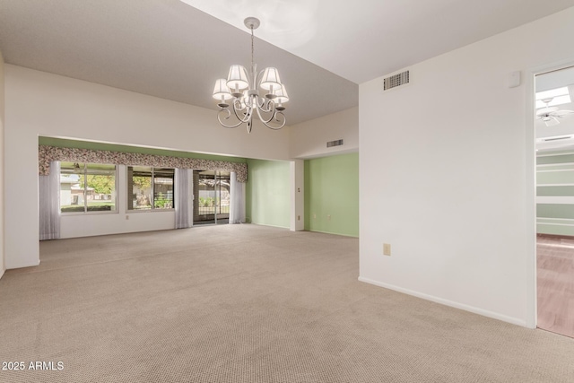 carpeted empty room with a chandelier, visible vents, and baseboards