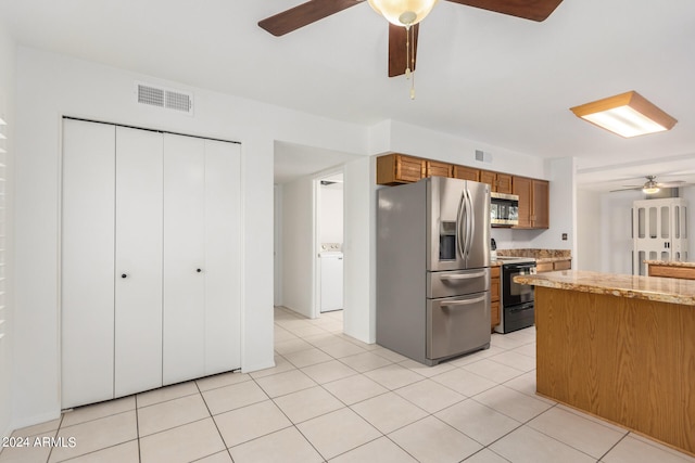 kitchen with light tile patterned flooring, washer / clothes dryer, ceiling fan, stainless steel appliances, and light stone countertops