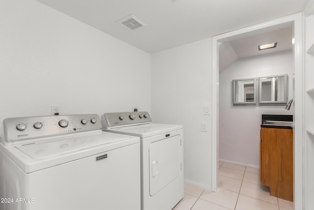 washroom with separate washer and dryer, light tile patterned floors, and sink