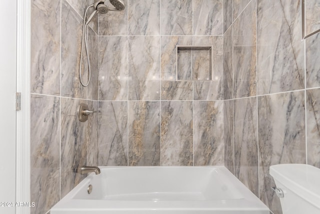 bathroom with tiled shower / bath combo, toilet, and tile walls