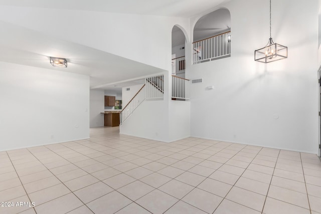 spare room with an inviting chandelier, a high ceiling, and light tile patterned floors