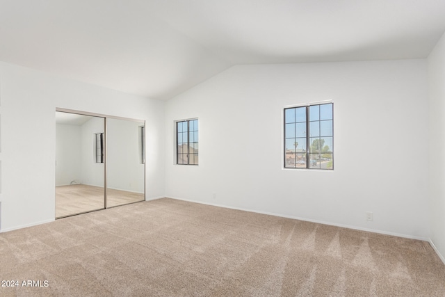 unfurnished bedroom with a closet, lofted ceiling, and light colored carpet