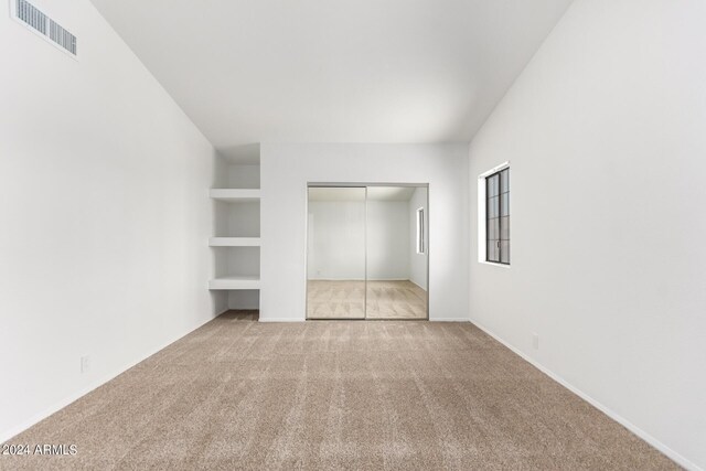 unfurnished bedroom with light carpet and a closet