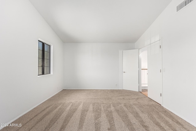 carpeted empty room featuring lofted ceiling