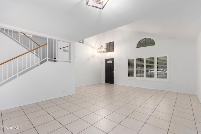 tiled empty room featuring high vaulted ceiling