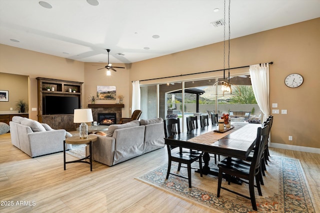 35971 N Prickley Pear Rd, Cave Creek, AZ 85331 - dining room featuring a glass covered fireplace, a ceiling fan, light wood-style floors, and baseboards