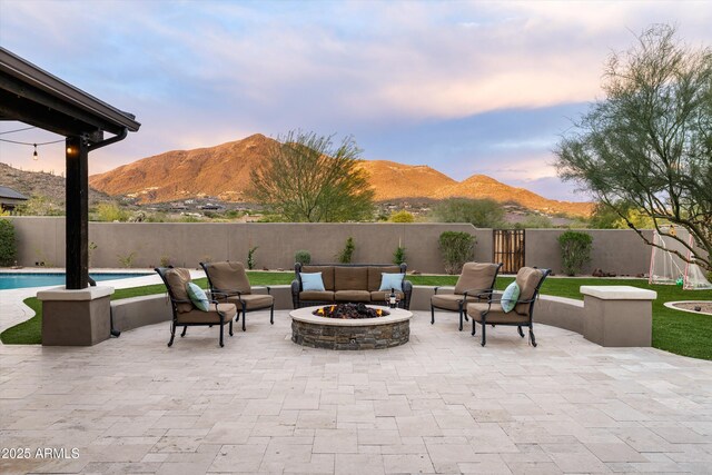 35971 N Prickley Pear Rd, Cave Creek, AZ 85331 - patio terrace at dusk with a mountain view, a fenced backyard, and an outdoor living space with a fire pit