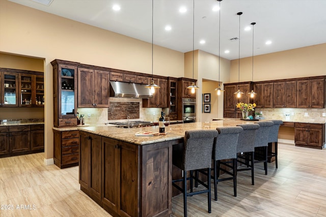 35971 N Prickley Pear Rd, Cave Creek, AZ 85331 - kitchen with under cabinet range hood, appliances with stainless steel finishes, tasteful backsplash, dark brown cabinets, and glass insert cabinets