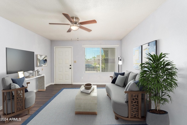 living room with ceiling fan, dark wood-type flooring, and a textured ceiling