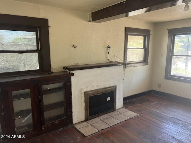 unfurnished living room with hardwood / wood-style flooring, a tiled fireplace, and beamed ceiling