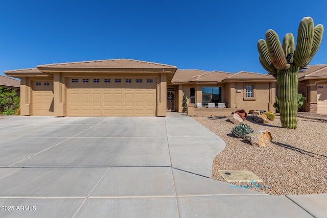 prairie-style home featuring stucco siding, an attached garage, a tile roof, and driveway