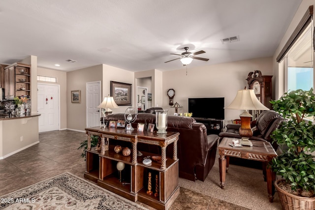 living area featuring visible vents, baseboards, and ceiling fan