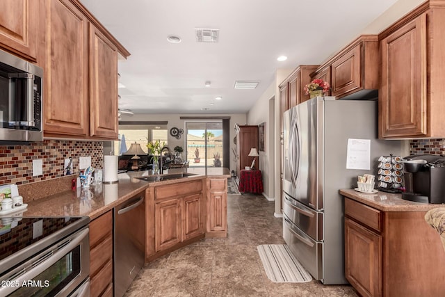 kitchen with a sink, stainless steel appliances, visible vents, and brown cabinetry