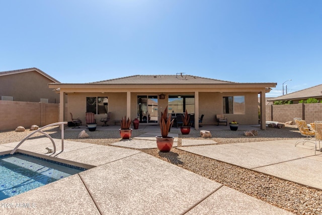 rear view of property with stucco siding, a tile roof, a patio, fence, and a fenced in pool