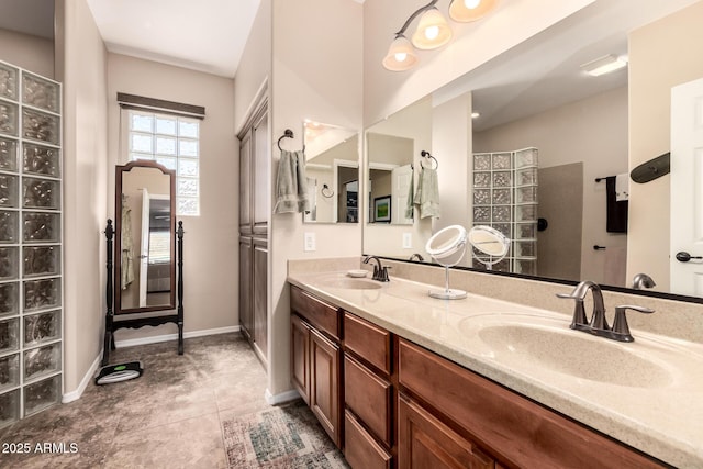 full bathroom featuring tile patterned flooring, double vanity, baseboards, and a sink