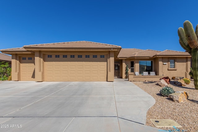 prairie-style home featuring stucco siding, a tiled roof, concrete driveway, and a garage