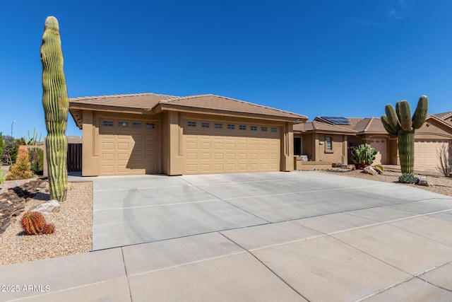 view of front of house with stucco siding, driveway, an attached garage, and a tile roof