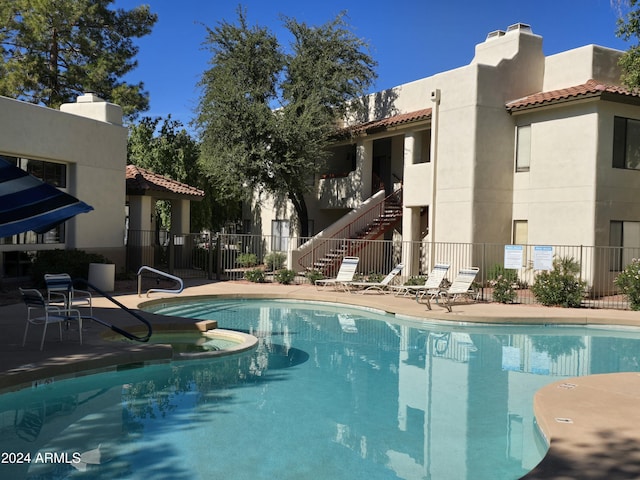 community pool with a patio area and fence