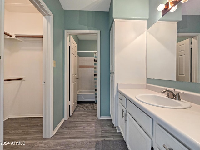 full bathroom with vanity, baseboards, a walk in closet, and wood finished floors