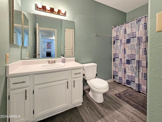 full bath featuring vanity, wood finished floors, toilet, and curtained shower