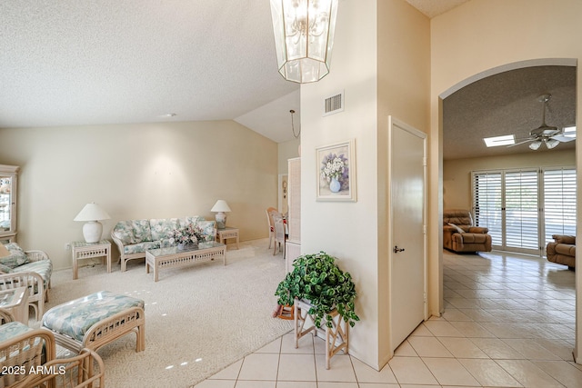 living room with light tile patterned floors, a textured ceiling, ceiling fan, and lofted ceiling