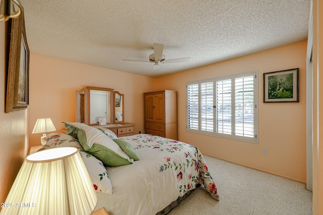 bedroom with ceiling fan, carpet floors, and a textured ceiling