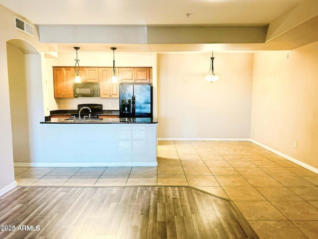 kitchen featuring decorative light fixtures, light hardwood / wood-style floors, sink, and black appliances