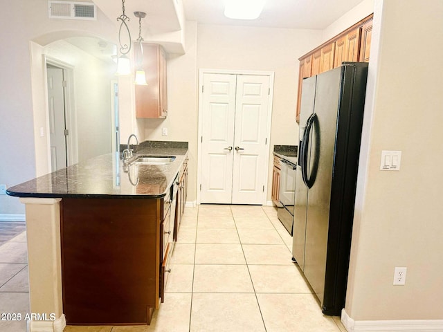 kitchen with hanging light fixtures, light tile patterned flooring, sink, and stainless steel fridge