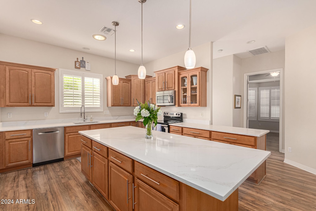 kitchen featuring sink, appliances with stainless steel finishes, hanging light fixtures, a center island, and dark hardwood / wood-style flooring