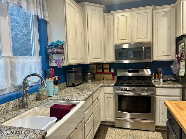 kitchen featuring wood counters, white cabinetry, sink, stainless steel appliances, and dark wood-type flooring