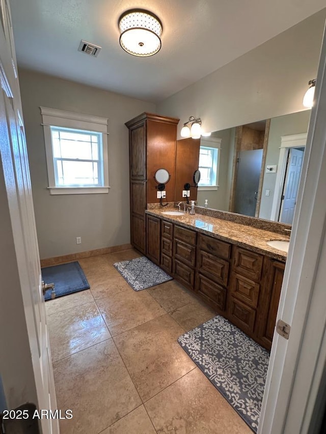 bathroom with visible vents, baseboards, double vanity, an enclosed shower, and a sink