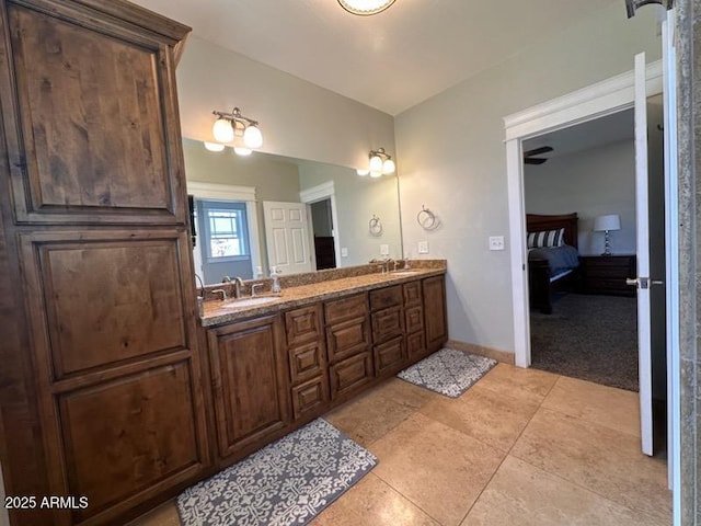 ensuite bathroom featuring double vanity, ensuite bath, baseboards, and a sink