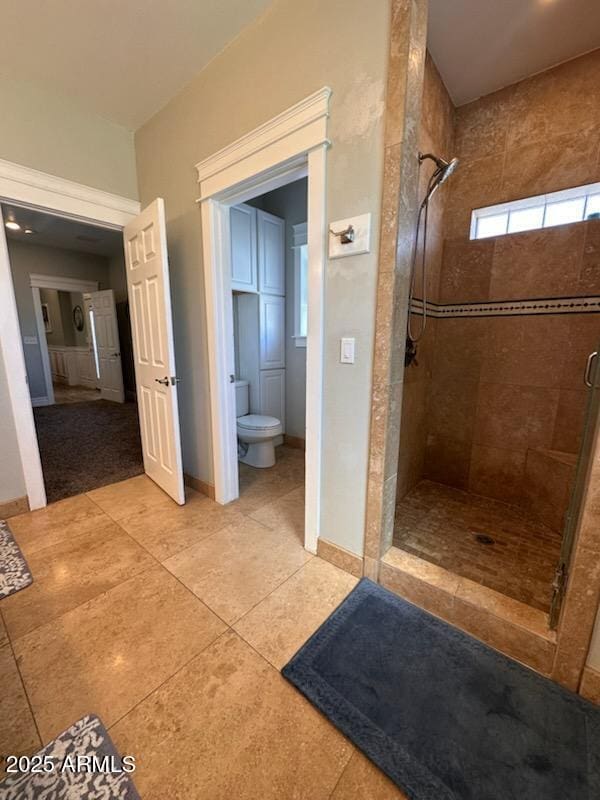 full bathroom featuring toilet, a stall shower, baseboards, and tile patterned floors