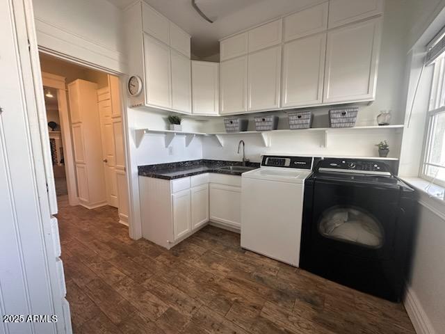 laundry room featuring dark wood finished floors, separate washer and dryer, cabinet space, and a sink
