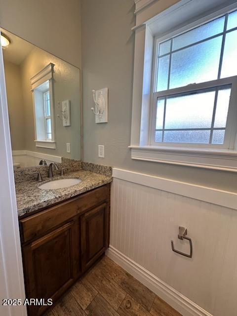 bathroom featuring vanity, wood finished floors, and wainscoting