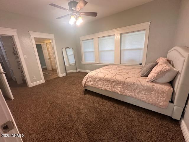 bedroom with a ceiling fan, baseboards, and dark carpet