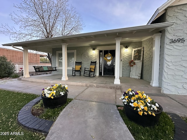 doorway to property featuring stone siding and a porch