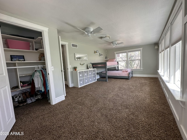 bedroom with a closet, a textured ceiling, visible vents, baseboards, and dark colored carpet