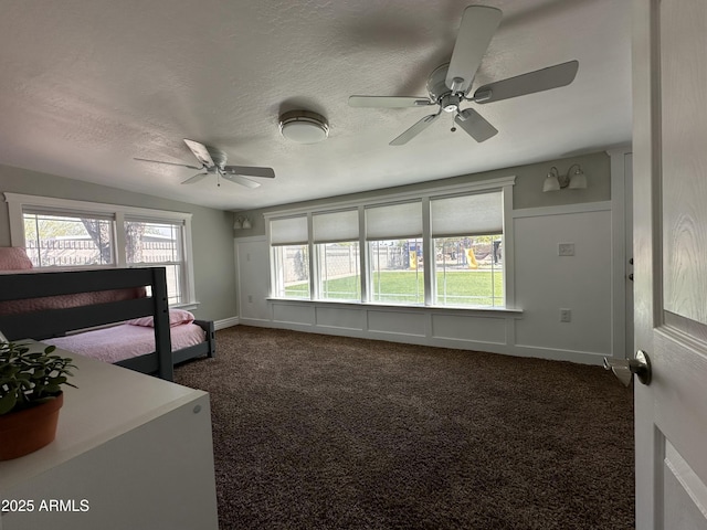 bedroom featuring multiple windows, dark carpet, and a textured ceiling