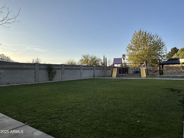 yard at dusk featuring a playground and fence