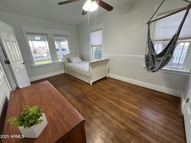unfurnished bedroom with a textured wall, baseboards, ceiling fan, and wood finished floors