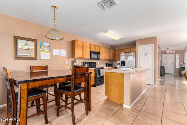 kitchen featuring pendant lighting, black appliances, a kitchen island, and light tile patterned floors