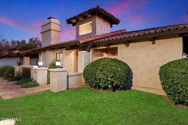 back house at dusk featuring a yard