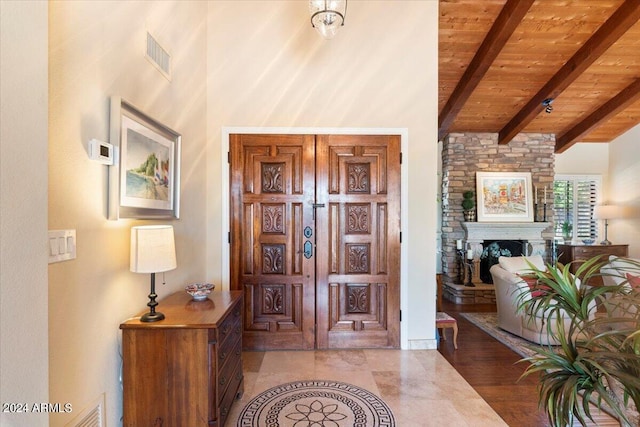 foyer entrance with wood ceiling, light wood-type flooring, and lofted ceiling with beams