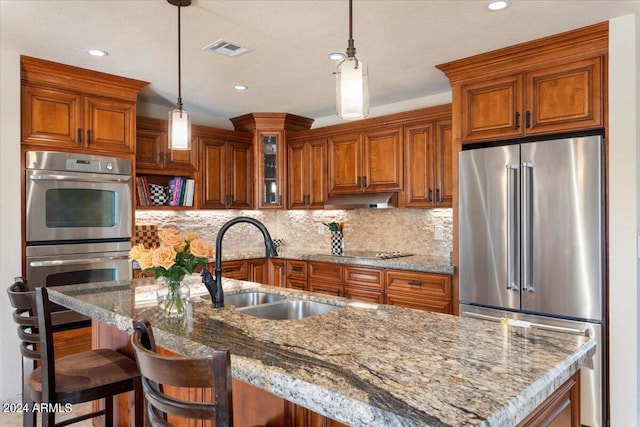 kitchen featuring light stone countertops, stainless steel appliances, a breakfast bar, and decorative light fixtures