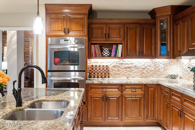 kitchen featuring decorative backsplash, double oven, pendant lighting, and sink